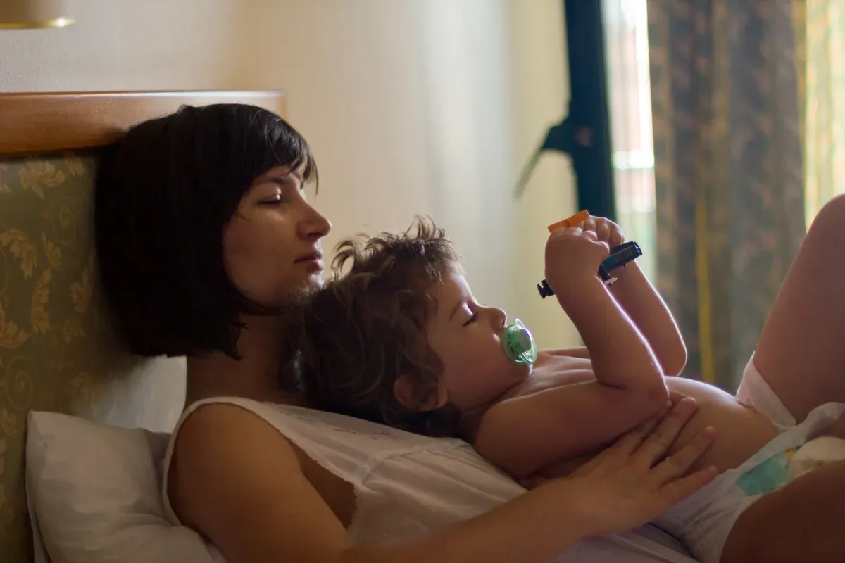Un adulto sdraiato accanto a un bambino piccolo che riposa nel letto